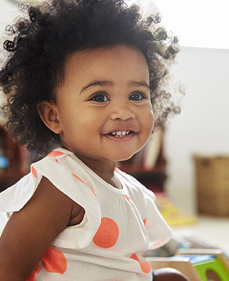 smiling girl playing with toys in the waiting area of village pediatric dentistry