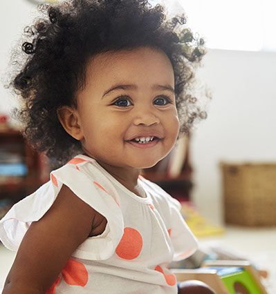 smiling girl playing with toys in the waiting area of village pediatric dentistry