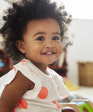 smiling girl playing with toys in the waiting area of village pediatric dentistry