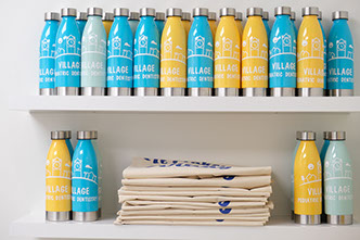shelf with yellow and blue water bottles with village pediatric dentistry logo printed on them
