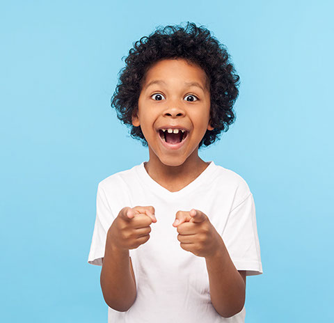 boy with a huge smile and curly hair pointing straight ahead