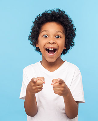 boy with a huge smile and curly hair pointing straight ahead